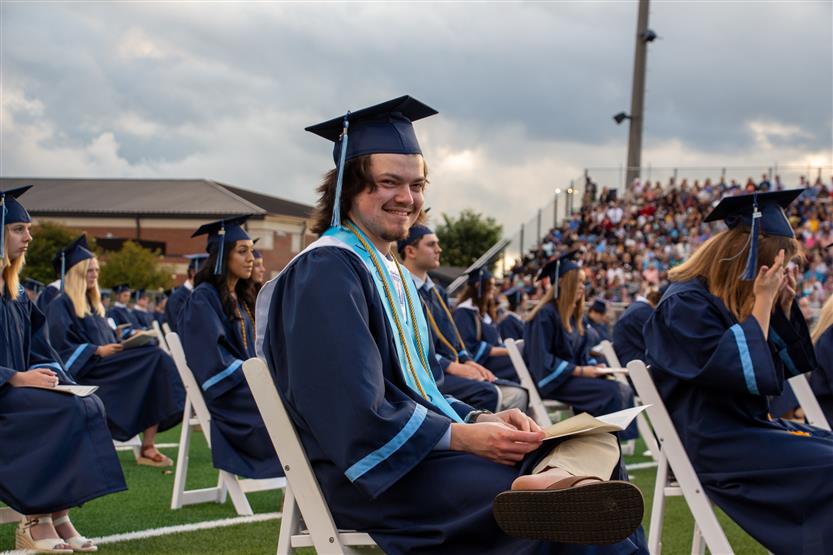 Students graduate outside on a football field